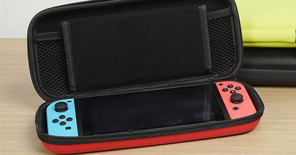 handheld gaming console inside red and black carrying case on table with black case and yellow case