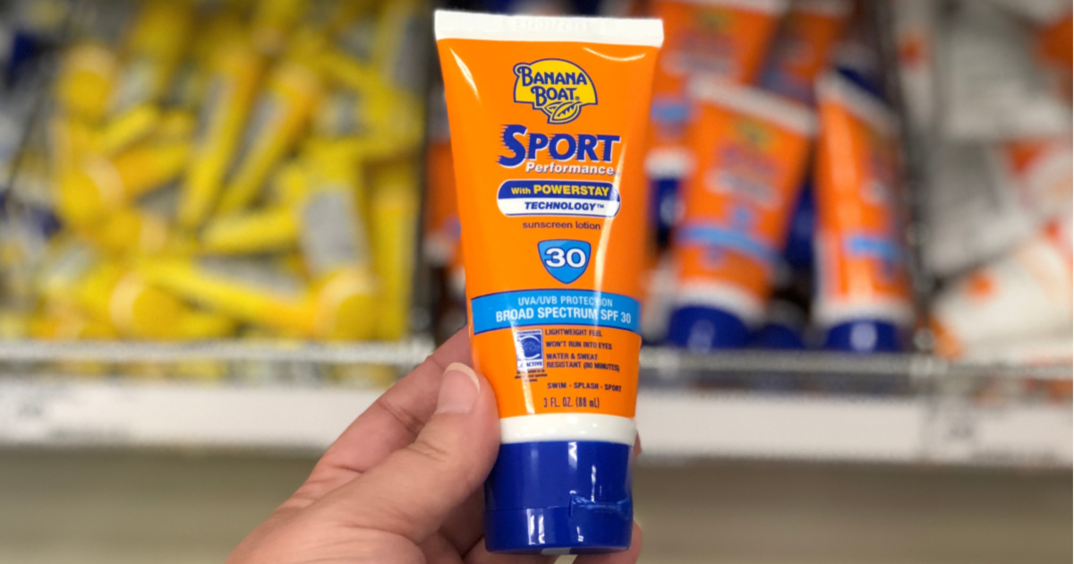 hand holding small orange tube of SPF 50 sunscreen in store aisle