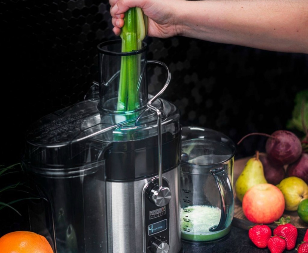 person adding celery to juicer