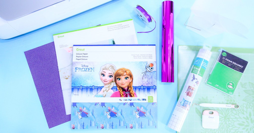 pack of disney frozen printed cricut paper on blue table surrounded by other cricut accessories and machine