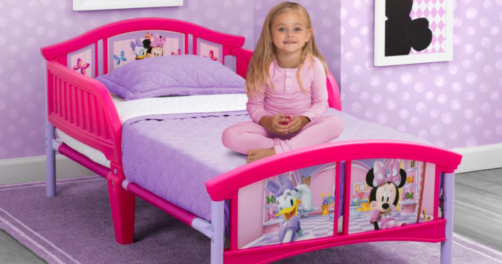 girl on pink Minnie Mouse bed with purple sheets