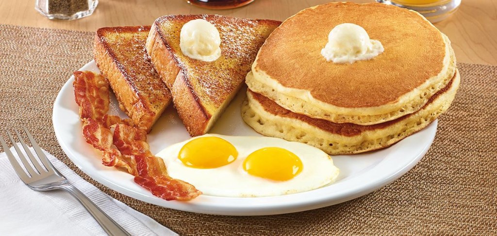 pancakes, french toast, eggs, and bacon on plate on table