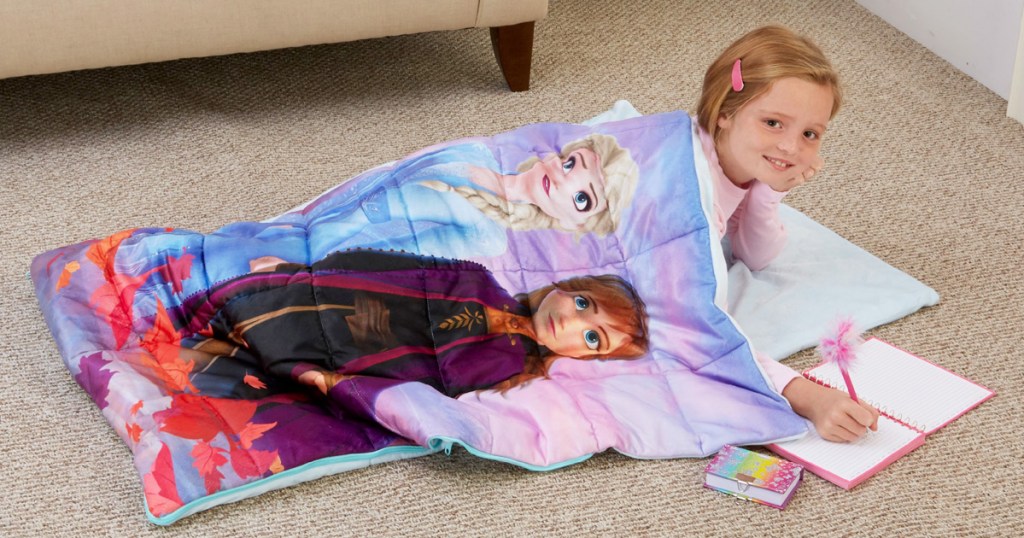 girl laying on floor inside disney frozen printed sleeping bag