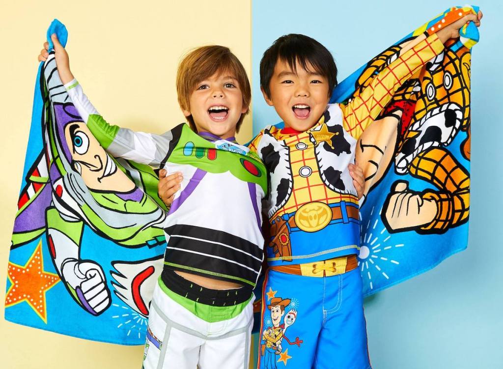 two boys in swimsuits holding up their towels