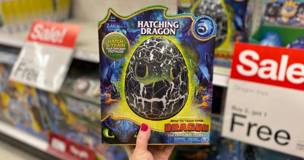 manicured hand holding hatching dragon egg toy in store