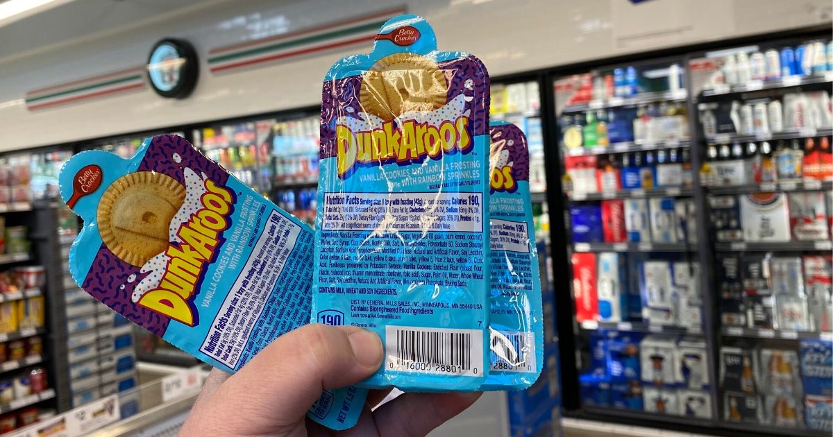 hand holding three dunkaroos in packs inside a convenience store