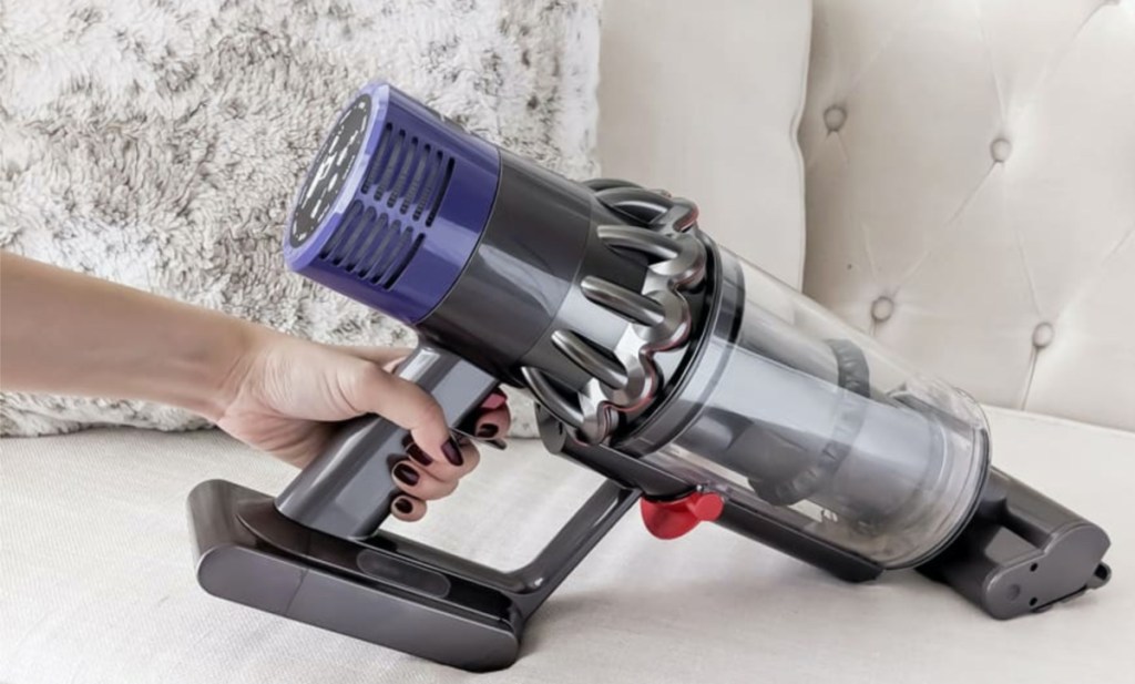 woman using vacuum attachment on white couch