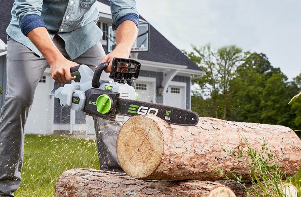 man using black and green chainsaw to cut tree