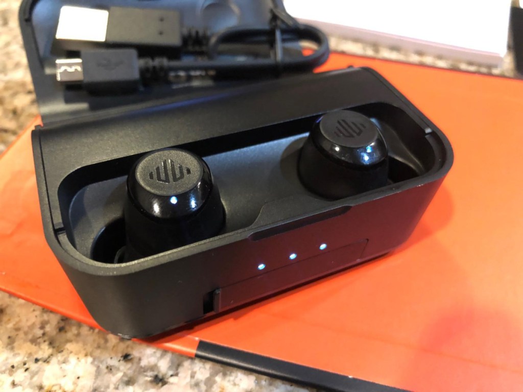 ear buds in charging case on orange surface