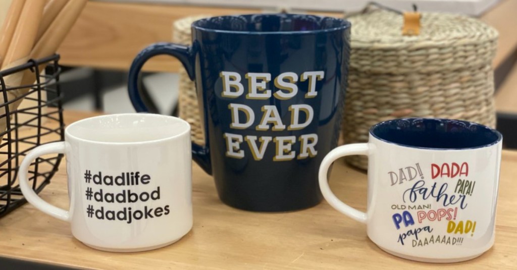 three Father's Day themed mugs on wood table in store