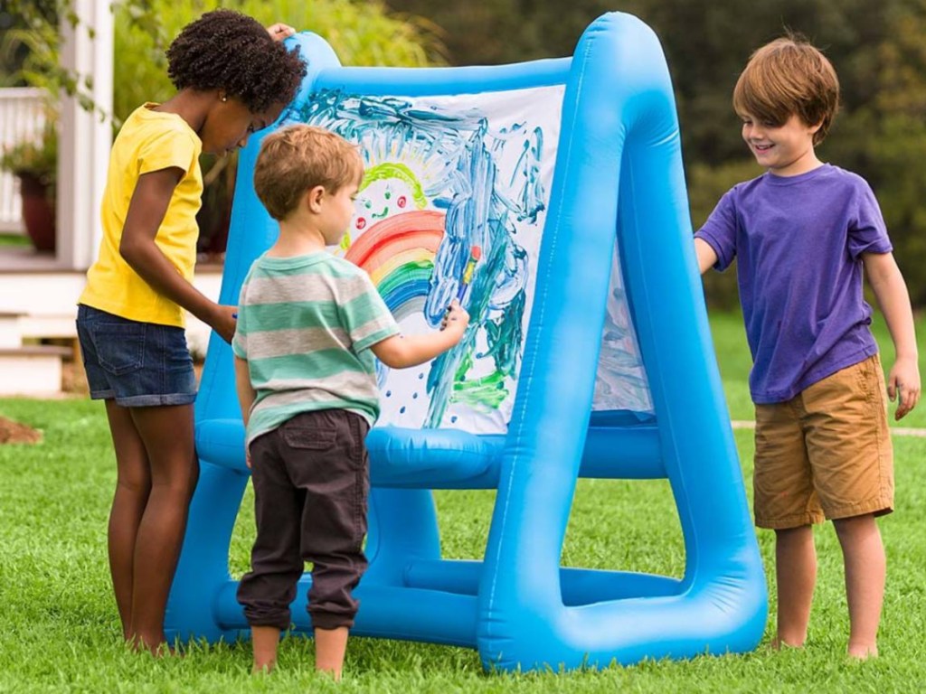 three children using blue inflatable double-sided easel outside