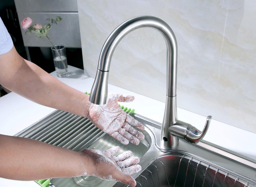 person washing hands at kitchen sink with silver faucet