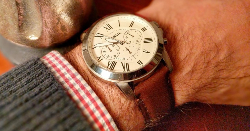 man wearing a fossil watch on his wrist with a white face and brown leather band