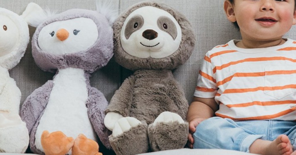 plush sloth sitting next to a baby and other plush animals