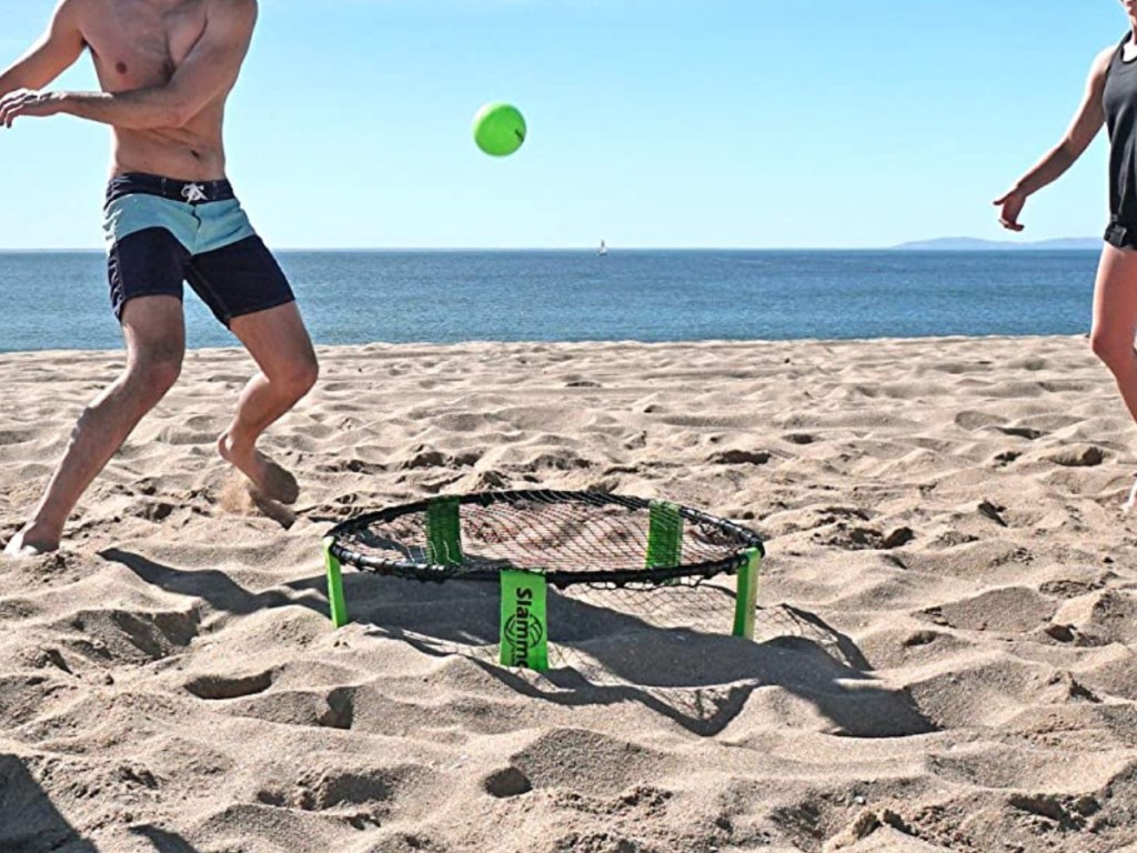 two men playing with tennis ball set on beach