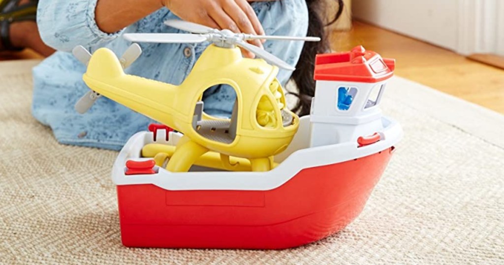 young girl playing with toy rescue boat on carpet