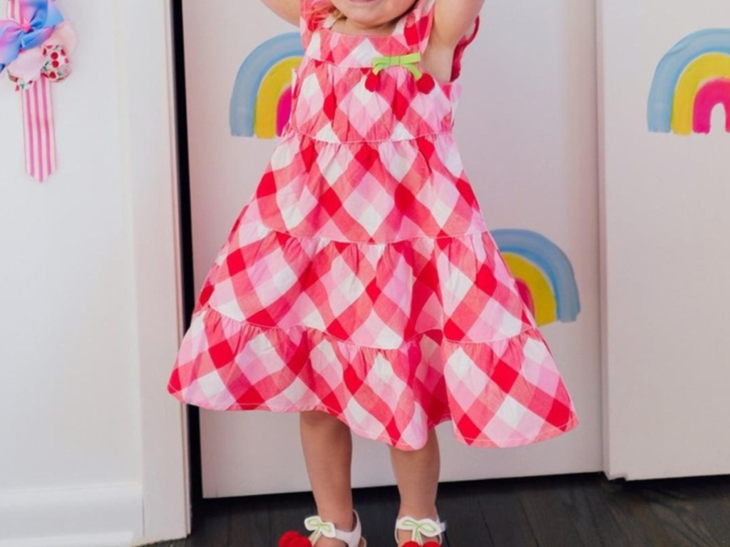 young girl in red and pink gingham dress with cherry design