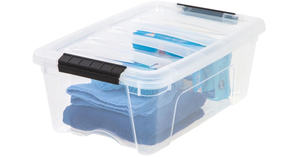 small clear plastic storage container with black latching handles filled with blue colored items inside