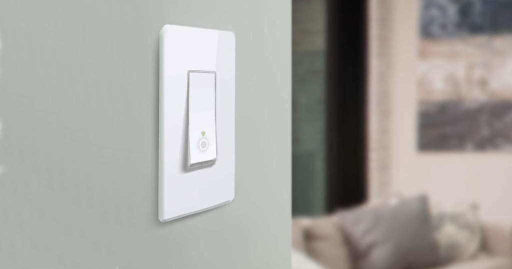 Single Kasa light switch on a green wall next to a living room