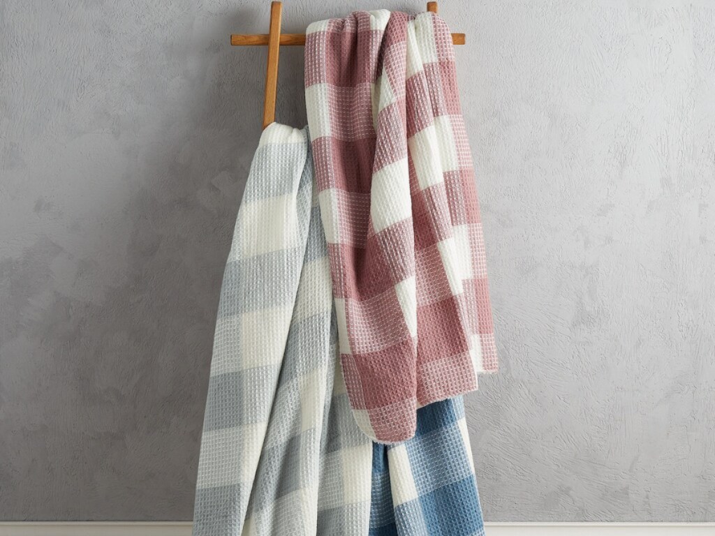 three checkered throws hanging on wooden rack