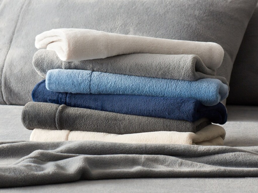 variety of colored sheets folded on grey blanket