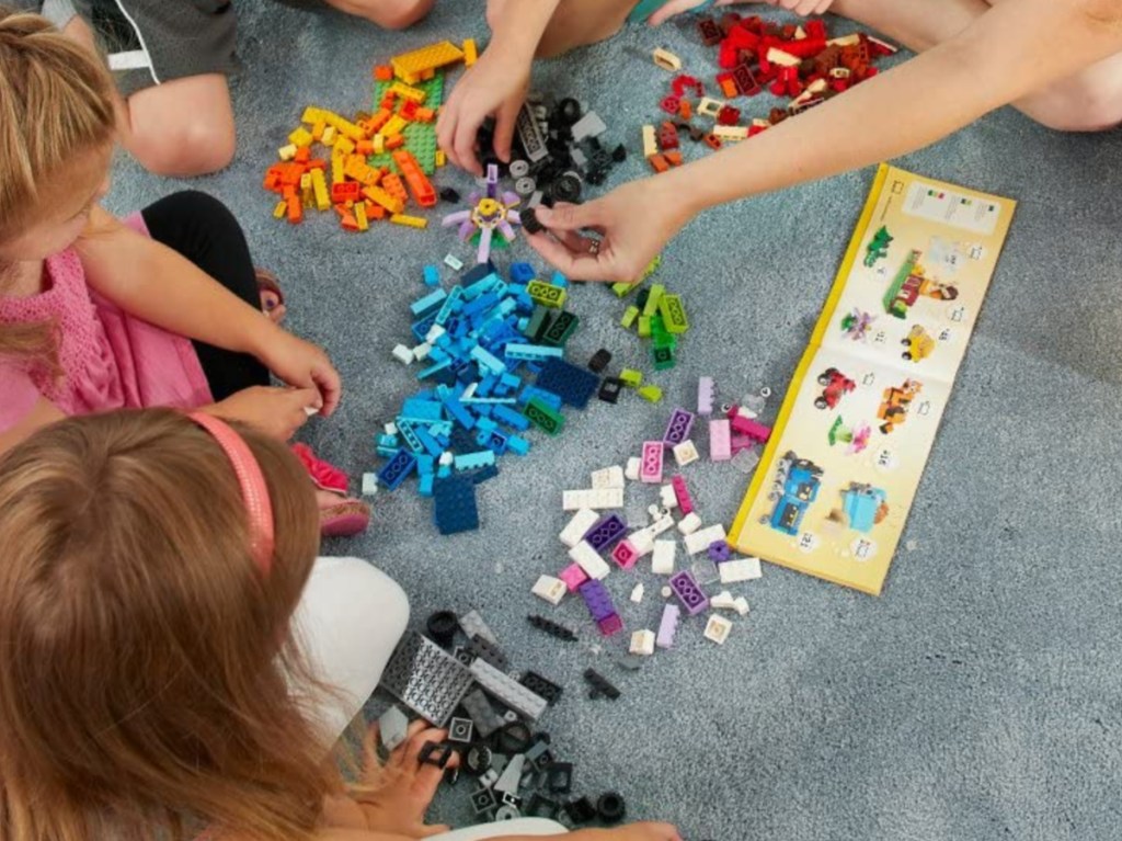 children and adult on carpet playing with building blocks