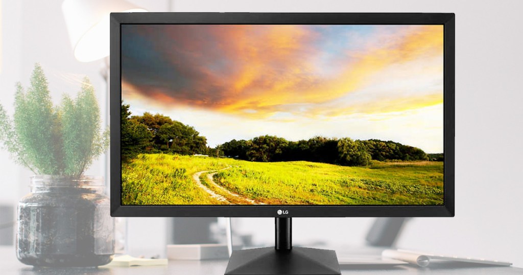 black computer monitor with field and sunset on screen on a desk