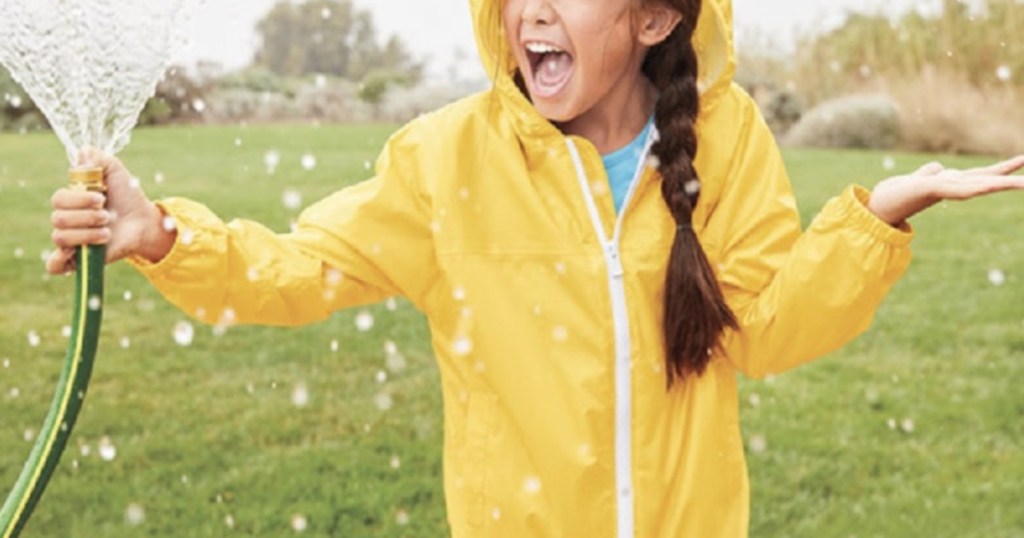 girl holding hose and wearing yellow hooded rain jacket