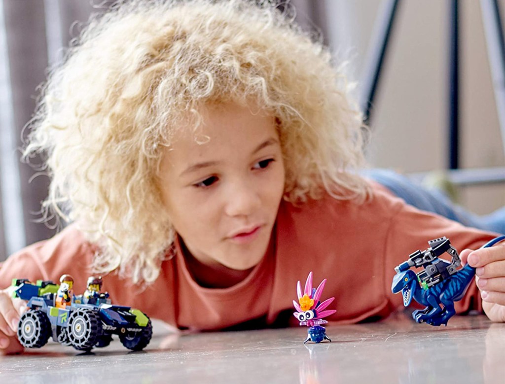 boy with blonde hair playing with lego movie figurines and car