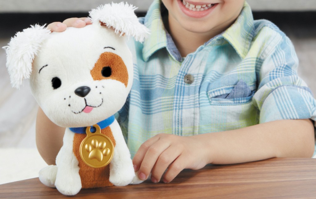 boy playing puppy plush toy on wood table