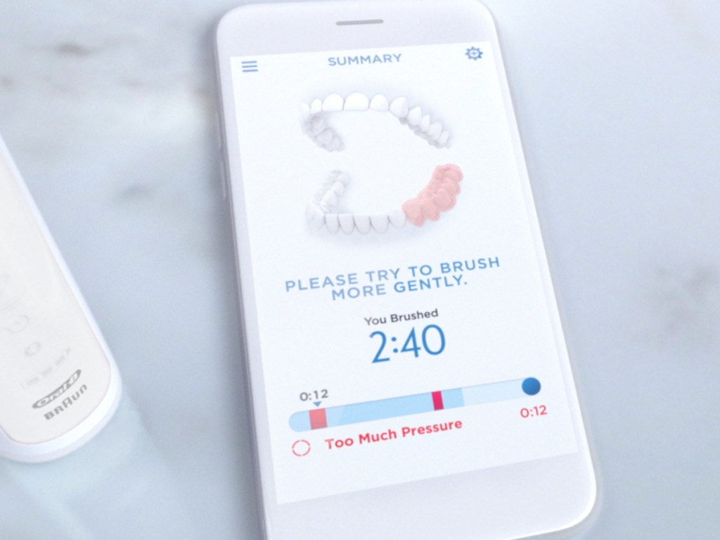 Oral-B 9600 Electric Toothbrush app on a smartphone next to a electric toothbrush