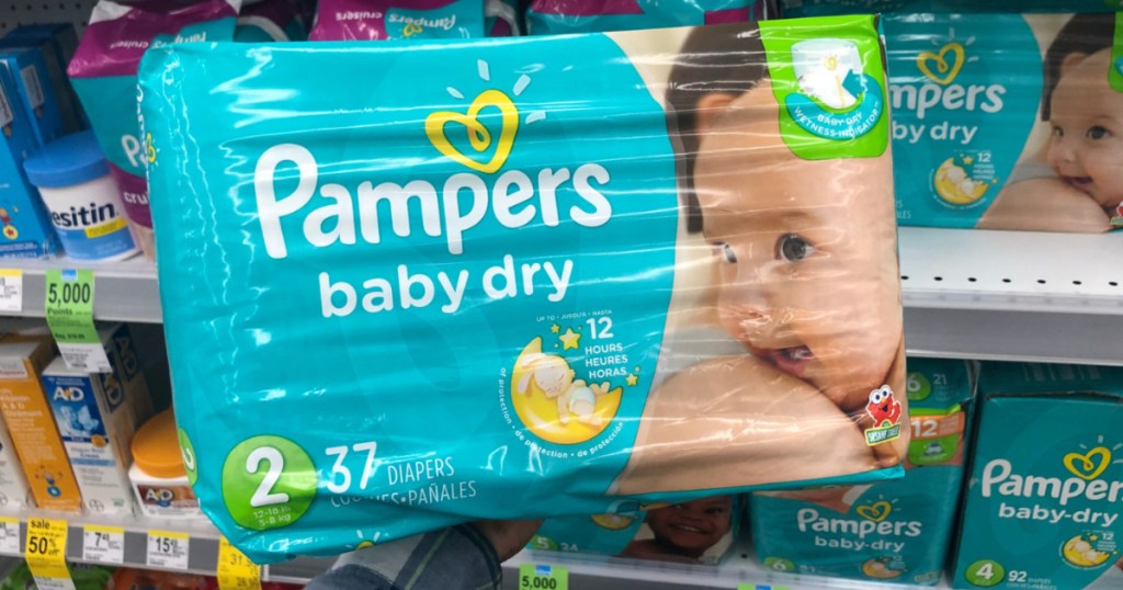hand holding jumbo pack of size 2 diapers in store aisle
