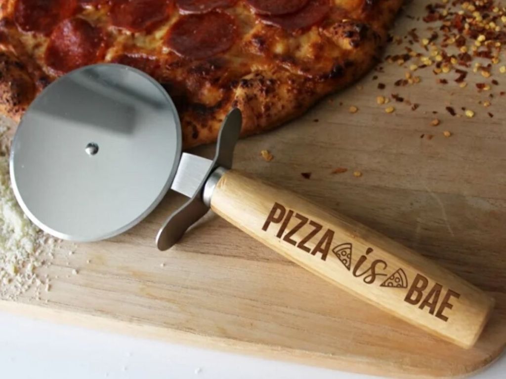 wooden pizza cutter on cutting board with pepperoni pizza