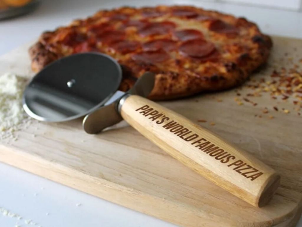 wooden pizza cutter on cutting board with pizza