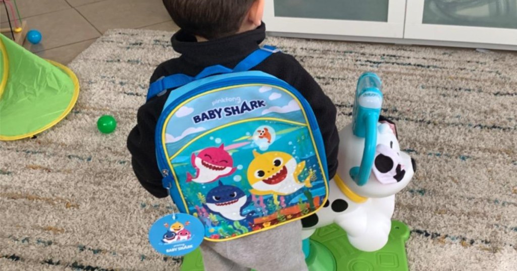 small child in home wearing blue Baby Shark backpack