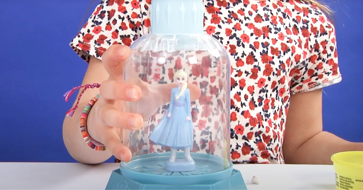 girl in floral shirt playing with a blue frozen 2 elsa play-doh snowglobe
