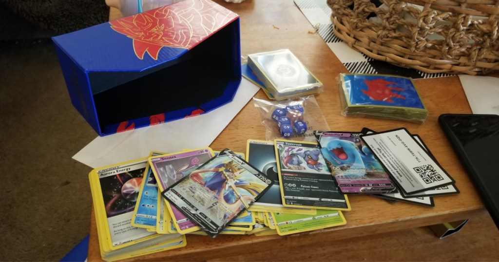 open Pokemon Trading Card Game: Sword and Shield Elite Trainer Box with cards, dice and more on table