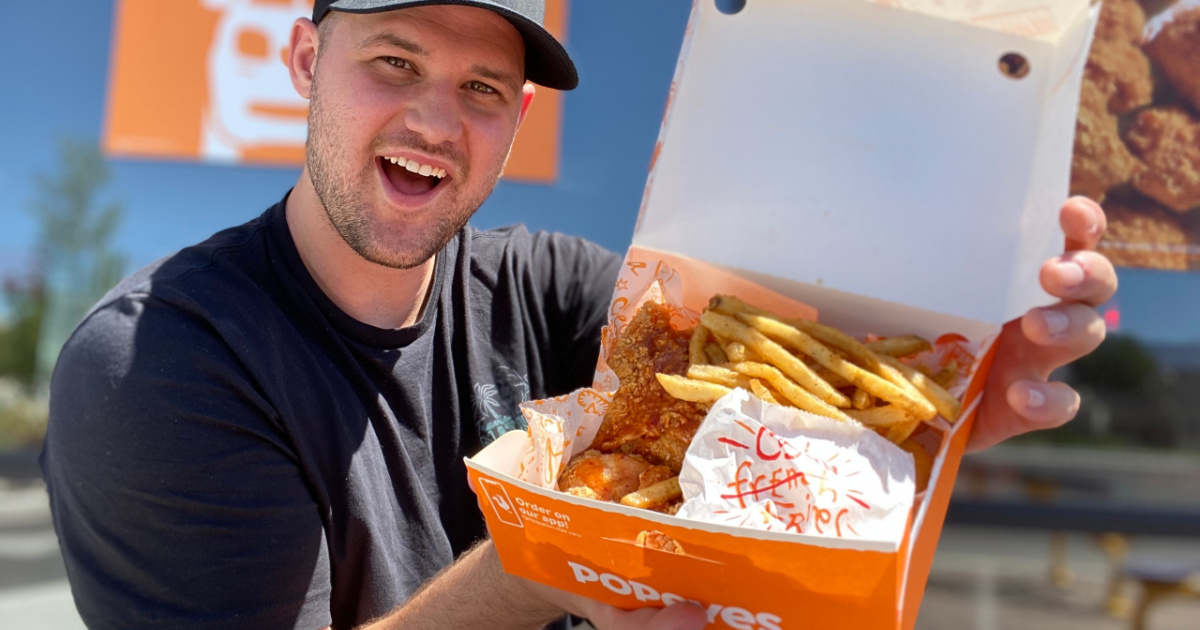 o homem em frente a um restaurante de fast food com uma caixa aberta de alimentos