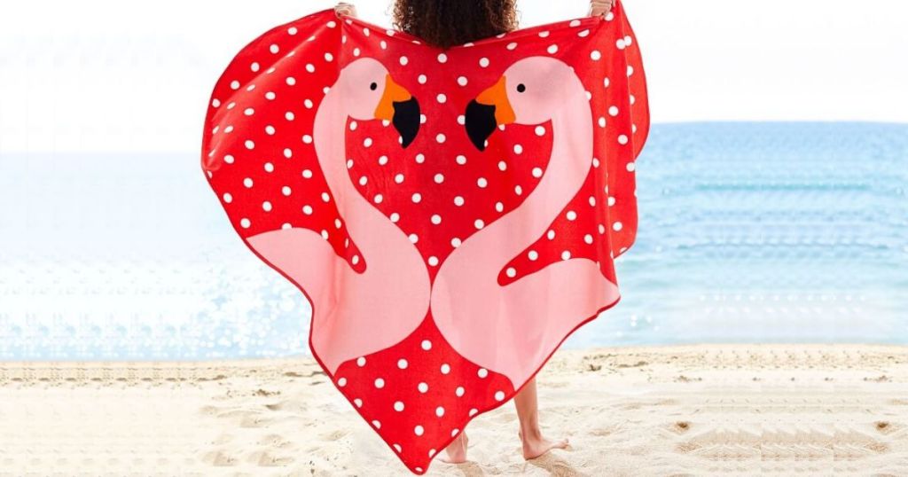 girl on beach holding up heart shaped towel