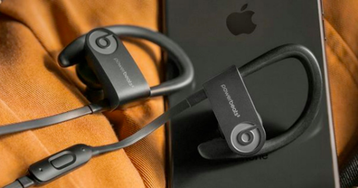 black powerbeats 3 earphones sitting next to a black iphone