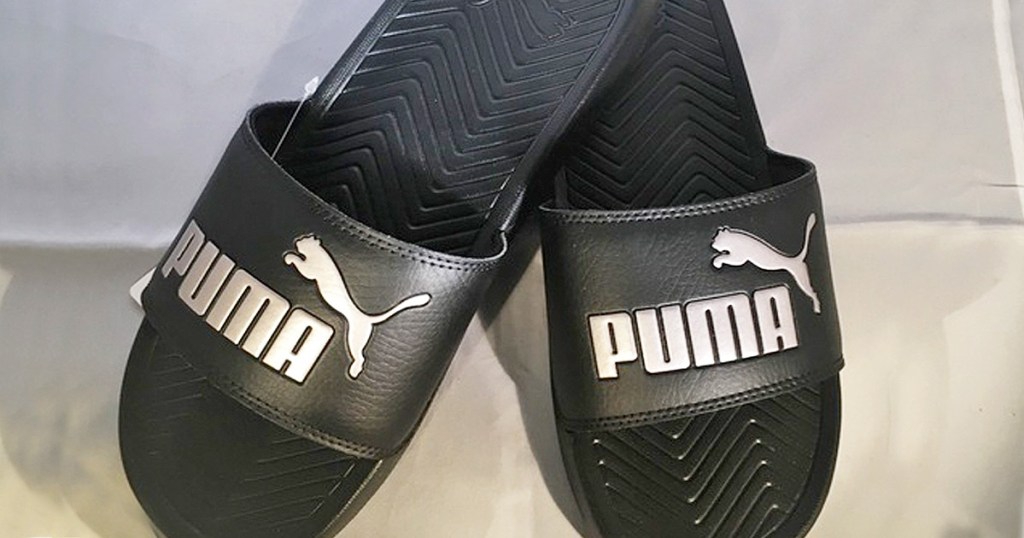 pair of black puma slides with white puma logo and cat on top straps