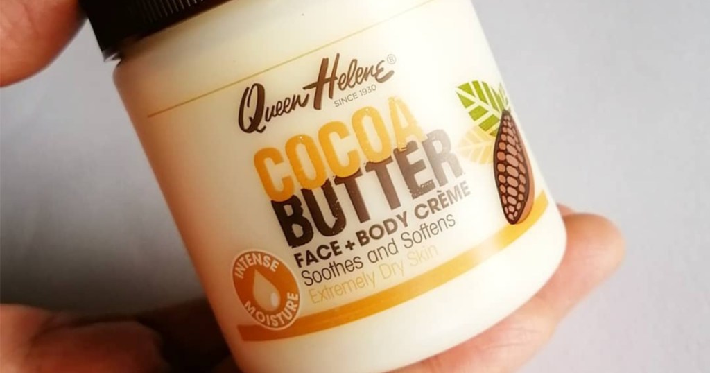 hand holding tub of cocoa butter lotion