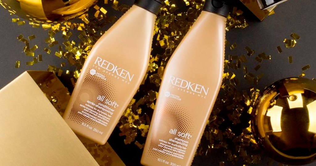 gold bottles of redken shampoo and conditioner on black table with gold confetti