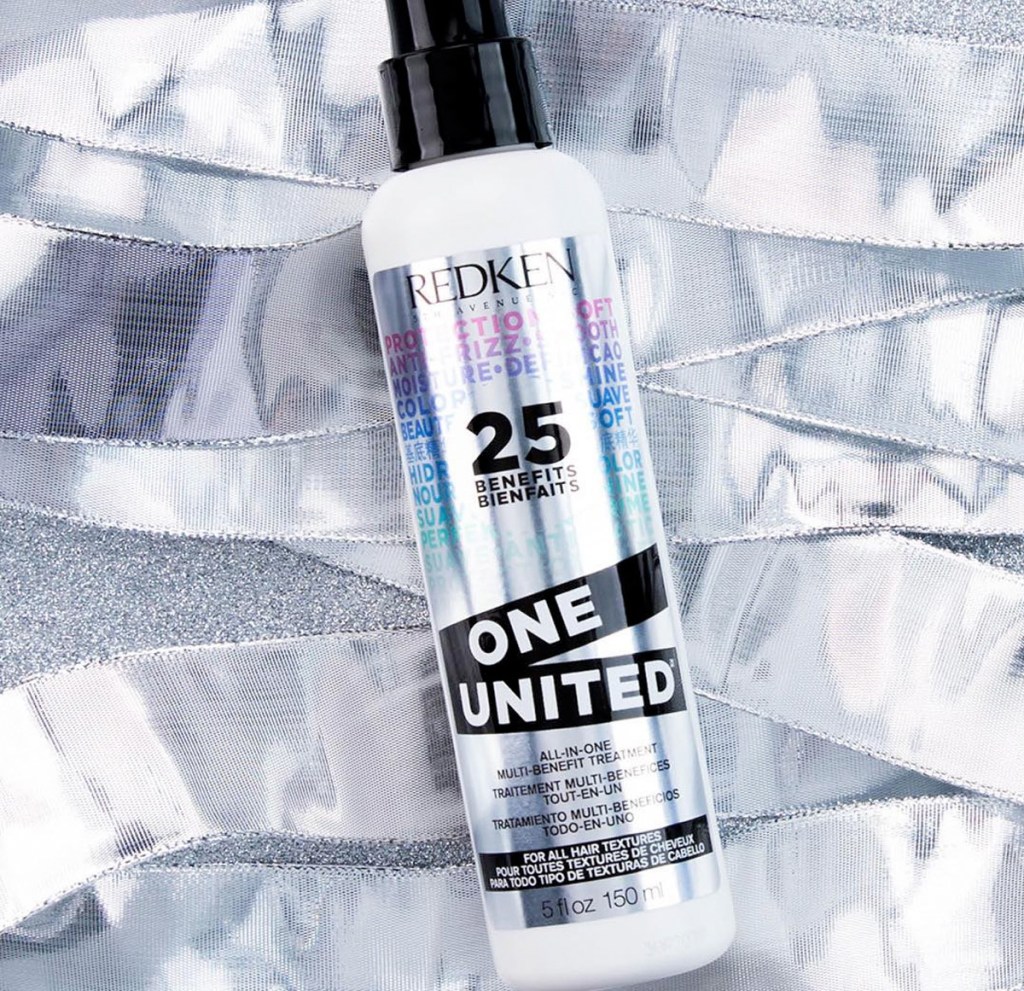 bottle of redken one united hair treatment spray laying on silver ribbons