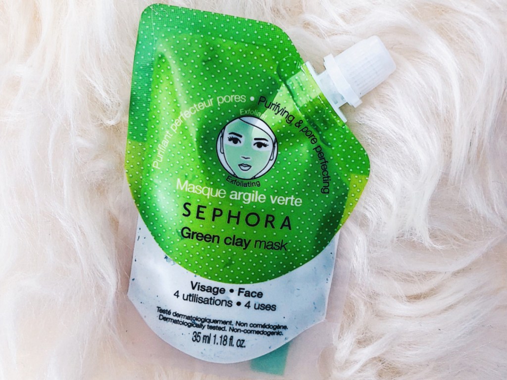 package of green clay face mask on white fur