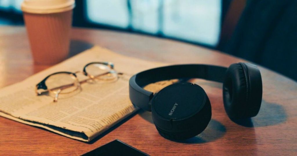 headphones on a table with magazine, glasses and coffee