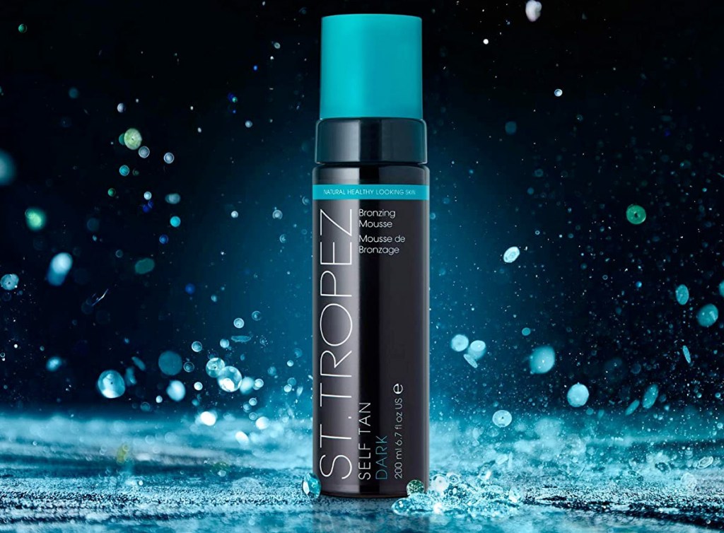 black and teal bottle of st tropez tanning lotion with water dropping around it