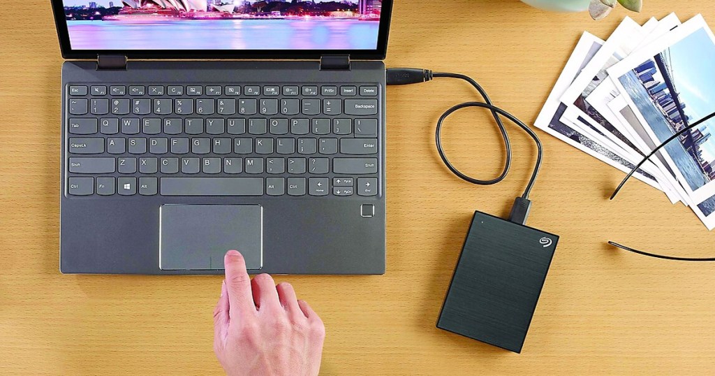 person using a black laptop with a black external hard drive connected to it