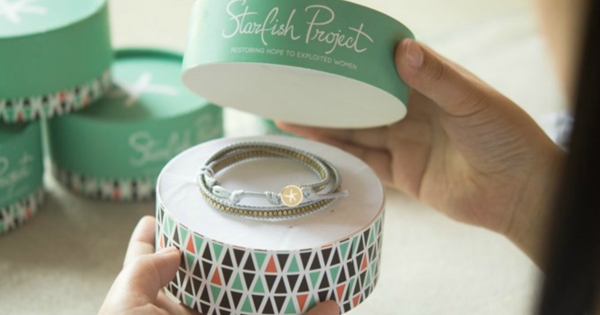 Hands opening a round colorful jewelry box with bracelet inside
