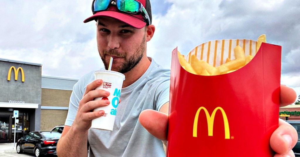 man holding McDonald's Fries and drink in Mcdonald's parking lot